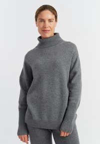 Maglione a collo alto grigio realizzato in morbido materiale a maglia, con una vestibilità comoda, polsini e orlo a costine e maniche lunghe, abbinato a pantaloni coordinati.