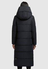 Dlhý čierny prešívaný kabát s veľkou kapucňou, horizontálnym prešívaním a bočnými vreckami na zips. Hladká, lesklá textura.