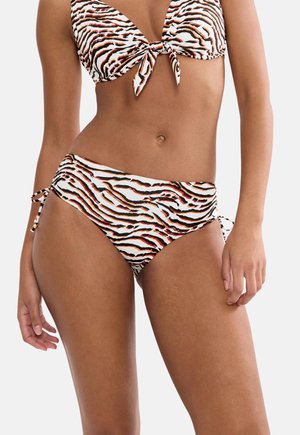 Femeie purtând un bikini cu dungi de tigru, cu nasturi în față pe partea de sus și cu legături laterale la partea de jos, vizibilă de la mijlocul pieptului până la coapsele superioare.