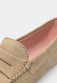 Beige semsket slip-on sko med rund tå, med dekorativt broderi og en glatt rosa innside.