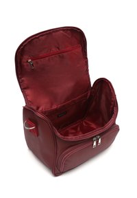 Neceser burdeos con exterior suave, parte superior con cremallera, bolsillo interior y un amplio interior forrado. Presenta un anillo de metal en el lateral.