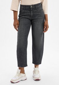 Donkergrijze denim jeans met een relaxte pasvorm, voorzien van zijzakken, een hoge taille en een nette afwerking bij de enkels. G gedragen met witte sneakers.