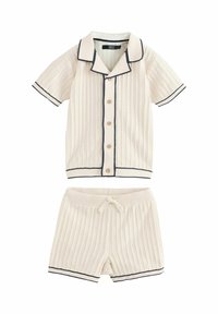 Pyjamasæt i cremefarvet ribbet stof med marineblå kant. Kortærmet skjorte med knapper og shorts med elastisk talje og snor.