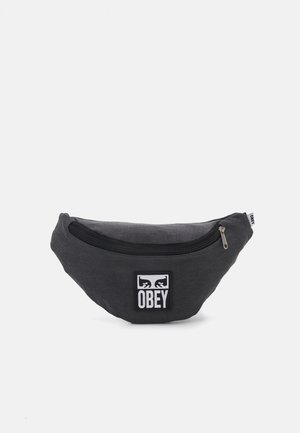 Riñonera de tela negra con forma curva, que presenta un compartimento frontal con cremallera y un parche con el logo "OBEY" en blanco.