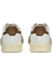 Weiße LederSneakers mit braunen Akzenten an der Ferse; abgerundetes Design, strukturiertes Material und dicke kremfarbene Sohlen.