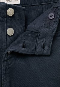 Tessuto denim blu navy con una superficie liscia, caratterizzato da due bottoni a pressione argentati, una chiusura a bottone nera e un piccolo dettaglio tasca.