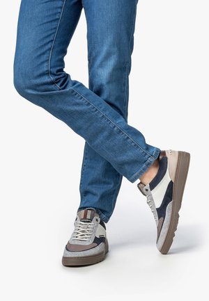 Multikleurige sneakers met een combinatie van grijze, marineblauwe en gebroken wit materialen, voorzien van een gestructureerde zool en opvallende veters.