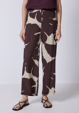 Wijdvallende broek met een bladerenpatroon in bordeauxrood en roomwit, met een elastische tailleband en lichte stof. Draagt gecombineerd met platte sandalen.