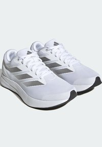 Baskets blanches en mesh et matière synthétique, avec trois rayures grises sur les côtés et une semelle extérieure en caoutchouc noir.