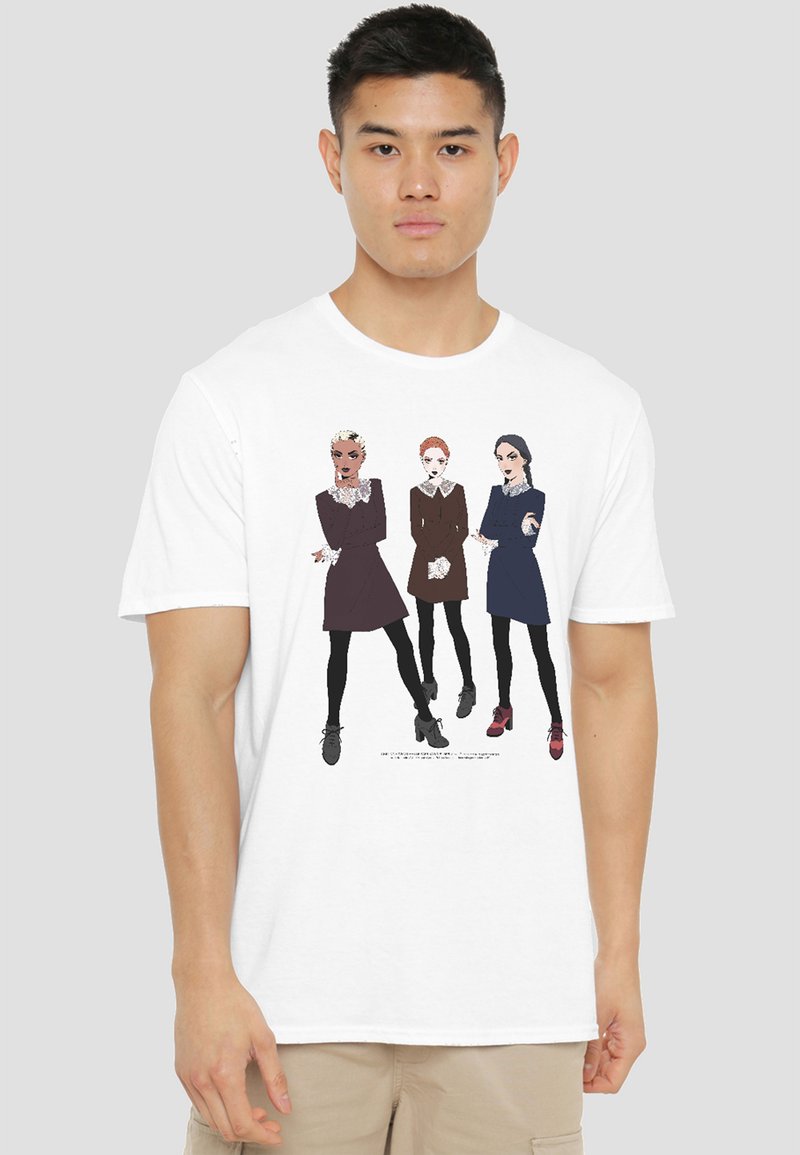 Young man wearing white T-shirt printed with three illustrated women in dresses, black tights, and high-heeled shoes, standing confidently.