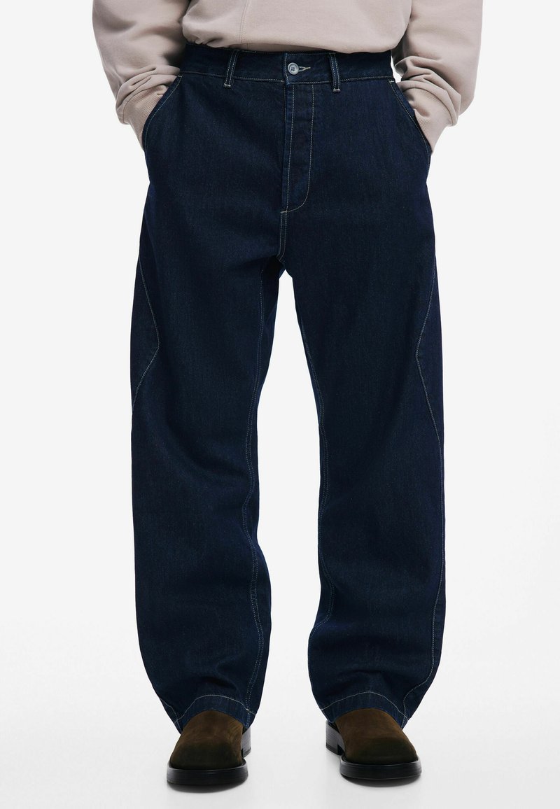 Dark blue denim jeans with a loose fit, featuring contrasting stitching, side pockets, and a flat front design.