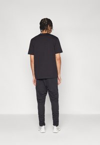 Melna T-kreklu un melnas kargo bikses, kokvilnas maisījums, brīva piegriezuma, apaļais kakls, teksturēts audums, ar kabatām, kombinēts ar baltām kedām.