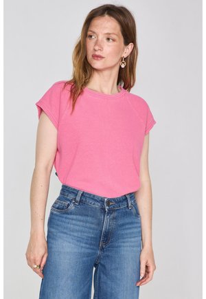T-shirt in cotone rosa con maniche corte, scollo rotondo e vestibilità rilassata, abbinato a jeans in denim blu a vita alta.