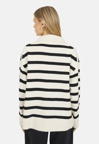 Cardigan a righe in crema e nero, con orlo e colletto a costine, dal fit rilassato e maniche lunghe. Morbido tessuto a maglia.