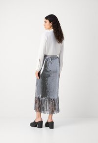 Sidabrinė blizgučiais sijonas su frandžo apdaila, derinamas su balta ilgomis rankovėmis blusa. Juodi platforminiai bateliai užbaigia aprangą. Tekstūra blizgi ir atspindinti.