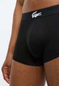 Boxers boxer noirs en coton avec une coupe ajustée, une ceinture élastique ornée d'un logo blanc, et une texture lisse.