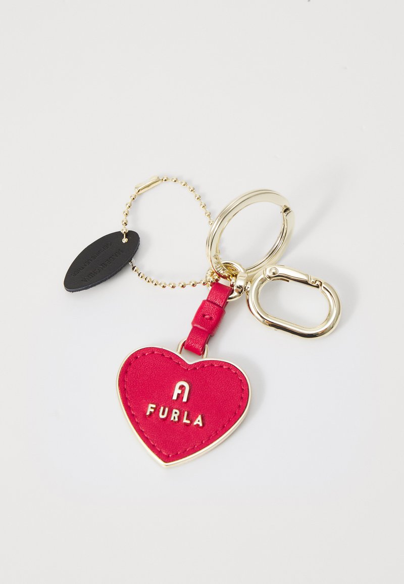 Crvena kožna privjesak u obliku srca s zlatnim dijelovima i utisnutim logotipom "FURLA". Sadrži zlatni lanac i crnu oznaku.