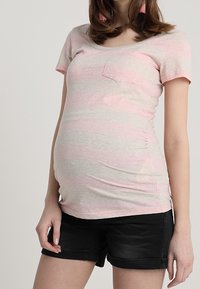 Graviditetst-shirt i ljusgrått med rosa ränder, korta ärmar, rundad halsringning och en liten ficka; bärs med svarta uppvikta shorts.