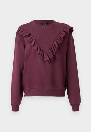 Burgundia värvi dressipluus, millel on volangiga V-kujuline kaelus, pikad varrukad ning soonikute äärised ja krae. Valmistatud pehmest kangast, millel on mugav lõige.