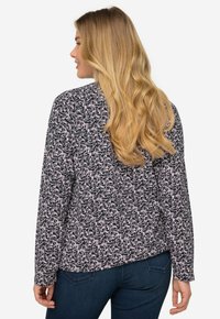 Blusa a maniche lunghe con un motivo floreale in bianco e nero. Tessuto morbido con una vestibilità comoda, scollatura rotonda e orlo leggermente curvo.