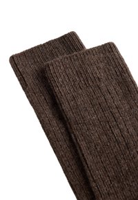Hnědé žebrované ponožky s texturovaným povrchem, s širokým lemem a měkkým tkaným materiálem, složené tak, aby byly vidět oba páry.