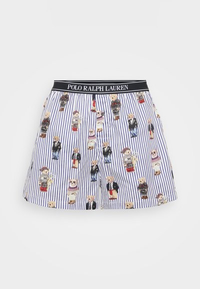 Bomullsshorts med ett blått och vitt randigt mönster, prytt med illustrerade nallar i olika kläder. Svart elastisk midjeband.