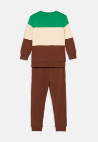Kindershirt met lange mouwen in groene, beige en bruine kleurvlakken, gecombineerd met effen bruine broek, beide in zachte stof.