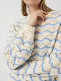 Pull en tricot crème avec un motif en vagues bleues, doté de poignets côtelés et d'une texture ajourée.