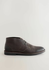 Bota de cuero marrón hasta el tobillo con punta redonda, diseño simple de cordones, textura suave y suela plana de goma negra.