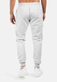 Grå mjukisbyxor med avslappnad passform, mudd vid anklarna och resår i midjan. Har sido- fickor med blixtlås och en mjuk, slät yta.