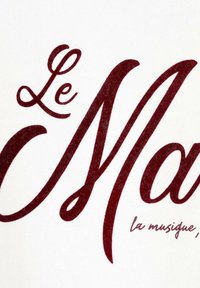 Un tissu blanc présente un grand texte bordeaux qui dit "Le Ma" avec une courbe sur la dernière lettre et un texte plus petit en dessous qui dit "la musique, (etc.)".