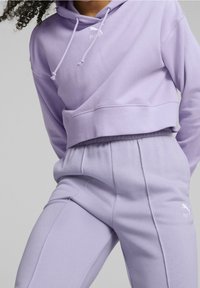 Sweat à capuche court lilas avec cordons et logo. Assorti à un pantalon de survêtement lilas avec une texture lisse et une taille élastique.