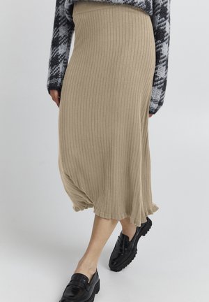 Beige ribstrikket midi-nederdel med flæsekant, båret med sorte loafers og en sort-hvid mønstret sweater.
