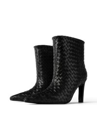 Czarne skórzane botki za kostkę z plecioną teksturą, spiczastym noskiem i szpilką. Projekt jest smukły z dopasowanym kostkiem.