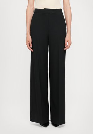 Pantalons larges noirs en tissu lisse avec une taille haute et un design classique. Présente un devant épuré sans matériel visible ni poches.