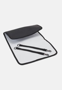 Černá syntetická taška s přehybovou klopou; vnitřek má bílou podšívku a dvě černé pásky s kovovými sponami.