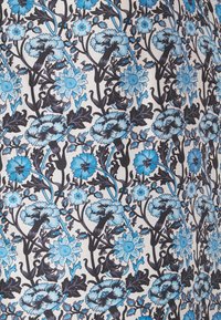 Motif floral bleu et noir avec diverses formes de fleurs et des feuilles sur un fond beige clair.