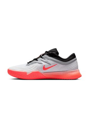 Witte en zwarte sport schoen met feloranje zool en Nike-swoosh, laag uitgesneden ontwerp en geprofileerde grip op de voorste buitenzool.