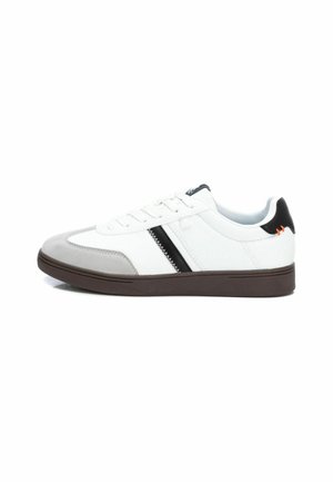 Zapatillas con una parte superior de cuero blanco, puntera de ante gris, franja de acento negra y una suela de goma marrón. Presenta cordones y un collar acolchado.