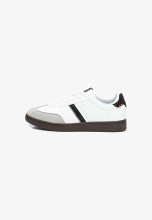 Zapatillas con una parte superior de cuero blanco, puntera de ante gris, franja de acento negra y una suela de goma marrón. Presenta cordones y un collar acolchado.