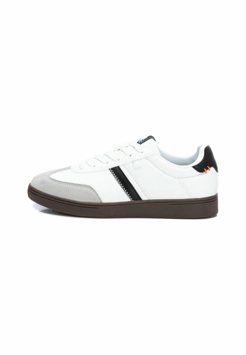 Zapatillas con una parte superior de cuero blanco, puntera de ante gris, franja de acento negra y una suela de goma marrón. Presenta cordones y un collar acolchado.