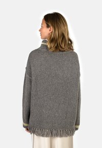 Gray knit sweater with a turtleneck, fringe hem, and gold-accented cuffs. Textured fabric with a loose fit and dropped shoulders.