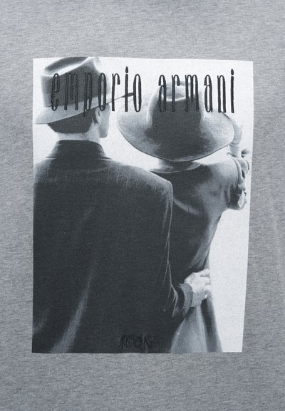 Γκρι κοντομάνικη μπλούζα με ασπρόμαυρο γραφικό δύο φιγούρων με καπέλα. Κείμενο "Emporio Armani" πάνω, με κέντημα "ICON" κοντά στο κάτω μέρος.