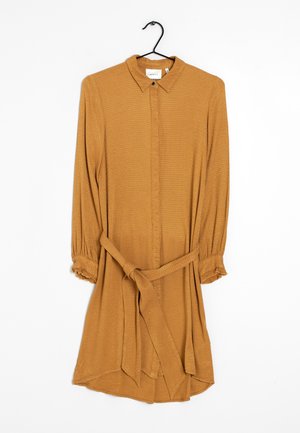 Robe chemise couleur moutarde avec un col à revers, manches longues, fermeture à boutons et ceinture nouée à la taille ; tissu texturé.