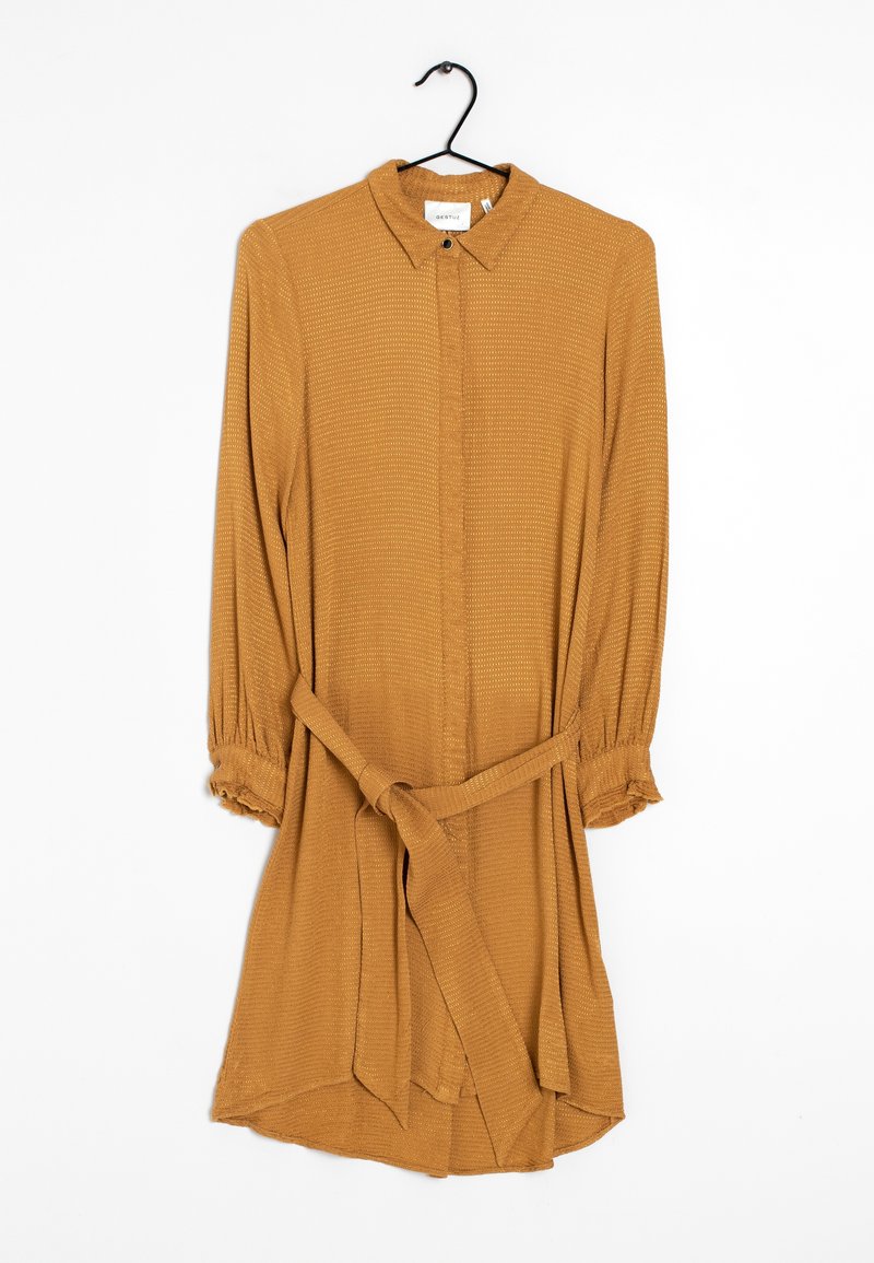 Robe chemise couleur moutarde avec un col à revers, manches longues, fermeture à boutons et ceinture nouée à la taille ; tissu texturé.