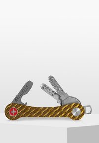 Multiverktyg med handtag i kolfiber i gul-brun, som har en kniv i rostfritt stål och en nyckelhållare med flera nyckelformer.