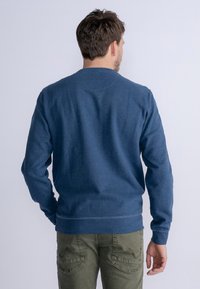 Sudadera oscura azul para hombres, con mangas largas, cuello redondo y puños y dobladillo acanalados. Textura suave y ajuste clásico.