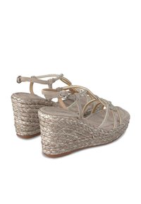 Wedge sandalen met een bovenwerk van beige suede, kruislings gespannen banden en metalen accenten. Gevlochten jute zool. Zacht tekstuur voetbed. Gesp sluiting.