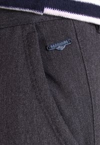 Poche de pantalon en tissu gris foncé avec une petite étiquette noire en métal de la marque Gabbiano fixée près du bord supérieur.