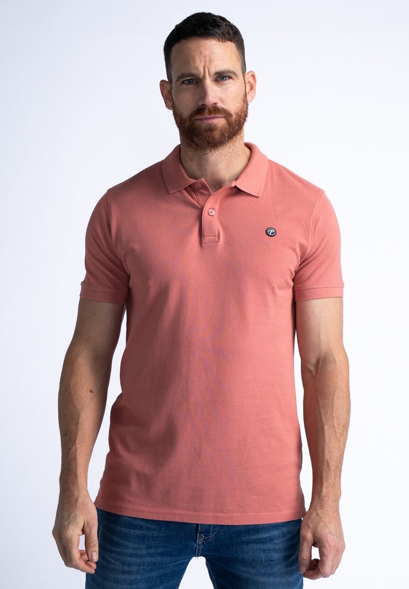 Polo à manches courtes en corail, avec un col et une patte de boutonnage à trois boutons. Petit logo sur la poitrine gauche. Fabriqué en tissu coton lisse.